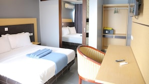 A hotel room with a bed, a chair, a desk, and a TV. - FINI Downtown (Limbe)