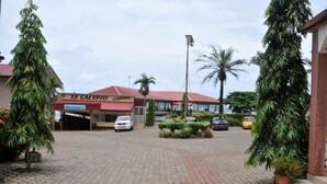 A paved entrance area with a building labeled "LE CALYPJO" and several parked cars. - FINI Downtown (Limbe)
