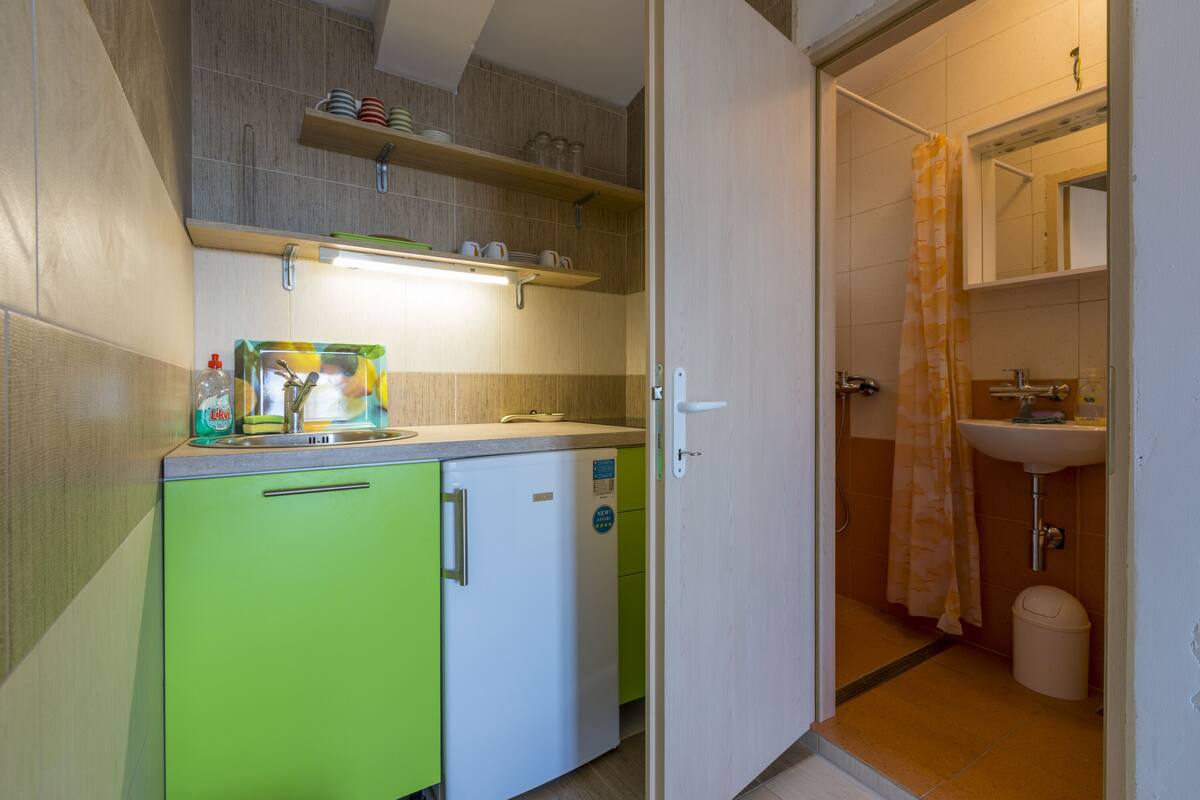 A compact kitchen with a refrigerator, a sink, and a countertop with various items.