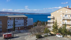 A coastal building with a view of the sea, a parking area, and a road with a truck. - Apartments Milan (Crikvenica)