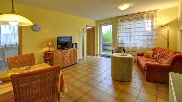 A living room with a television, sofa, and dining area with chairs and a table. - Inselblume 41 - 42 (Fehmarn)