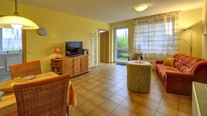 A living room with a television, sofa, and dining area with chairs and a table. - Inselblume 41 - 42 (Fehmarn)