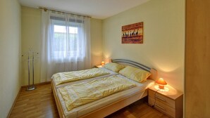 A double bed with two bedside tables, a window with sheer curtains, and a wall-mounted painting. - Inselblume 41 - 42 (Fehmarn)