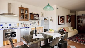 Een keuken met een eettafel, stoelen, een fornuis, oven en kastjes.