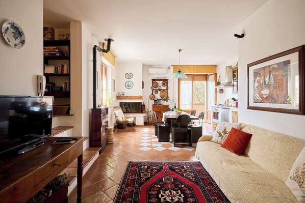 A living room with a TV, sofa, and a dining area with chairs and a table.