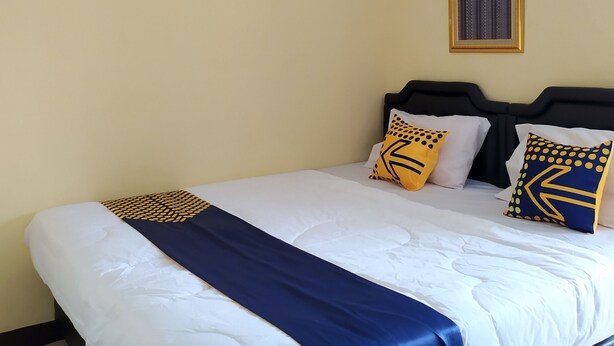 Ein Hotelzimmer mit einem Bett, einem Kopfteil und einer wandmontierten Klimaanlage.