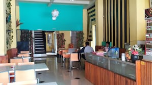 Ein Restaurant mit einer türkisblauen Wand, einer Holztresen und mehreren Tischen und Stühlen.