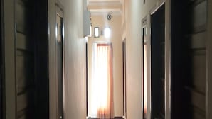 Ein Flur mit Türen an beiden Seiten, der zu einem Raum mit Fenster und Vorhängen führt.