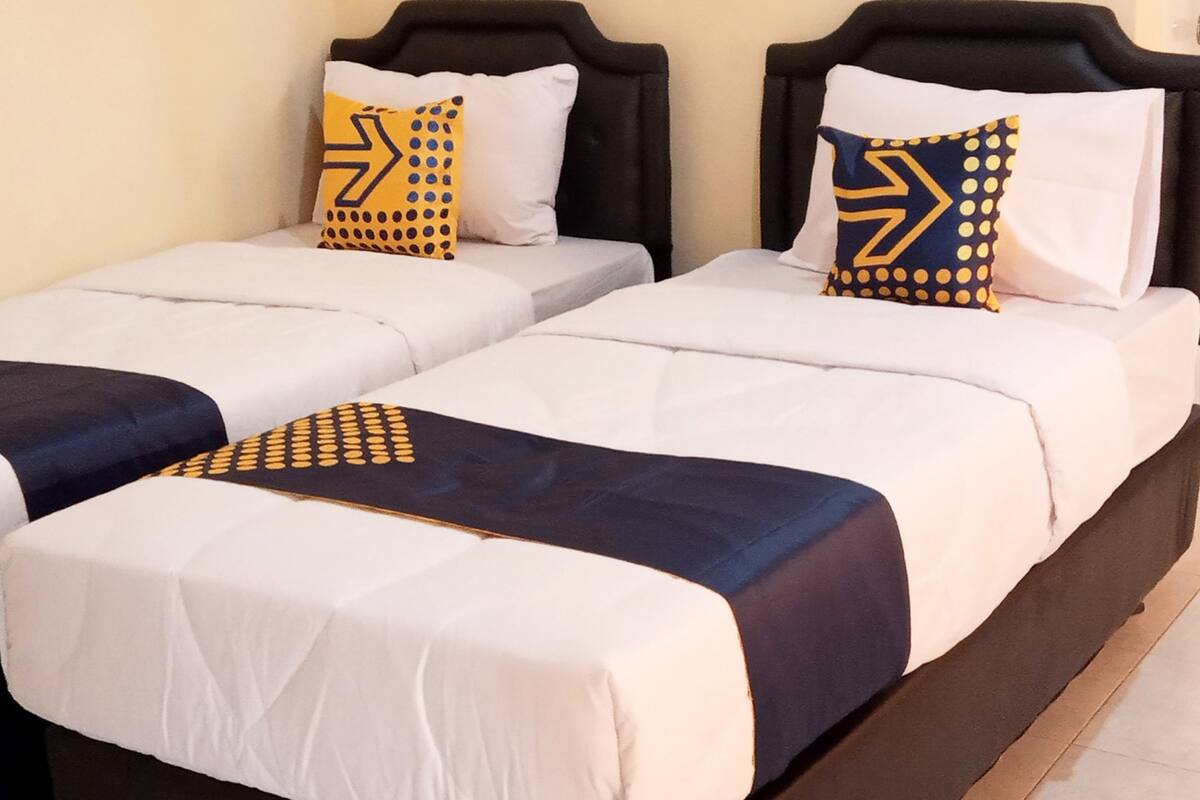 A double bed with a black headboard and white bedding, featuring two decorative pillows with a geometric pattern.