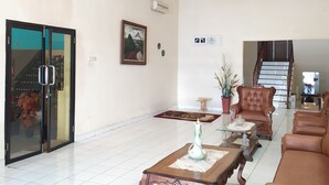 Ein geräumiges Wohnzimmer mit einer Chandelieber, einer Treppe und einem großen Fenster.