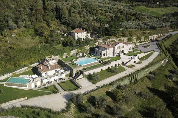 An aerial view of a large estate with multiple buildings, a swimming pool, and well-maintained gardens. - Villa Caiano (Londa)