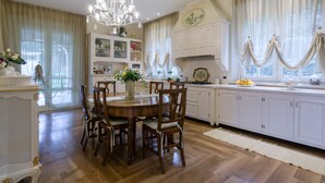 A dining area with a wooden table and chairs, a chandelier, and a white cabinet with glass doors. - Villa Caiano (Londa)