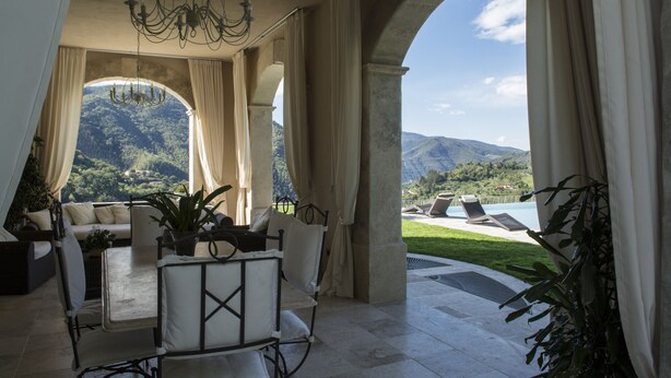 A spacious room with a view of mountains, a chandelier, and a pool area. - Villa Caiano (Londa)