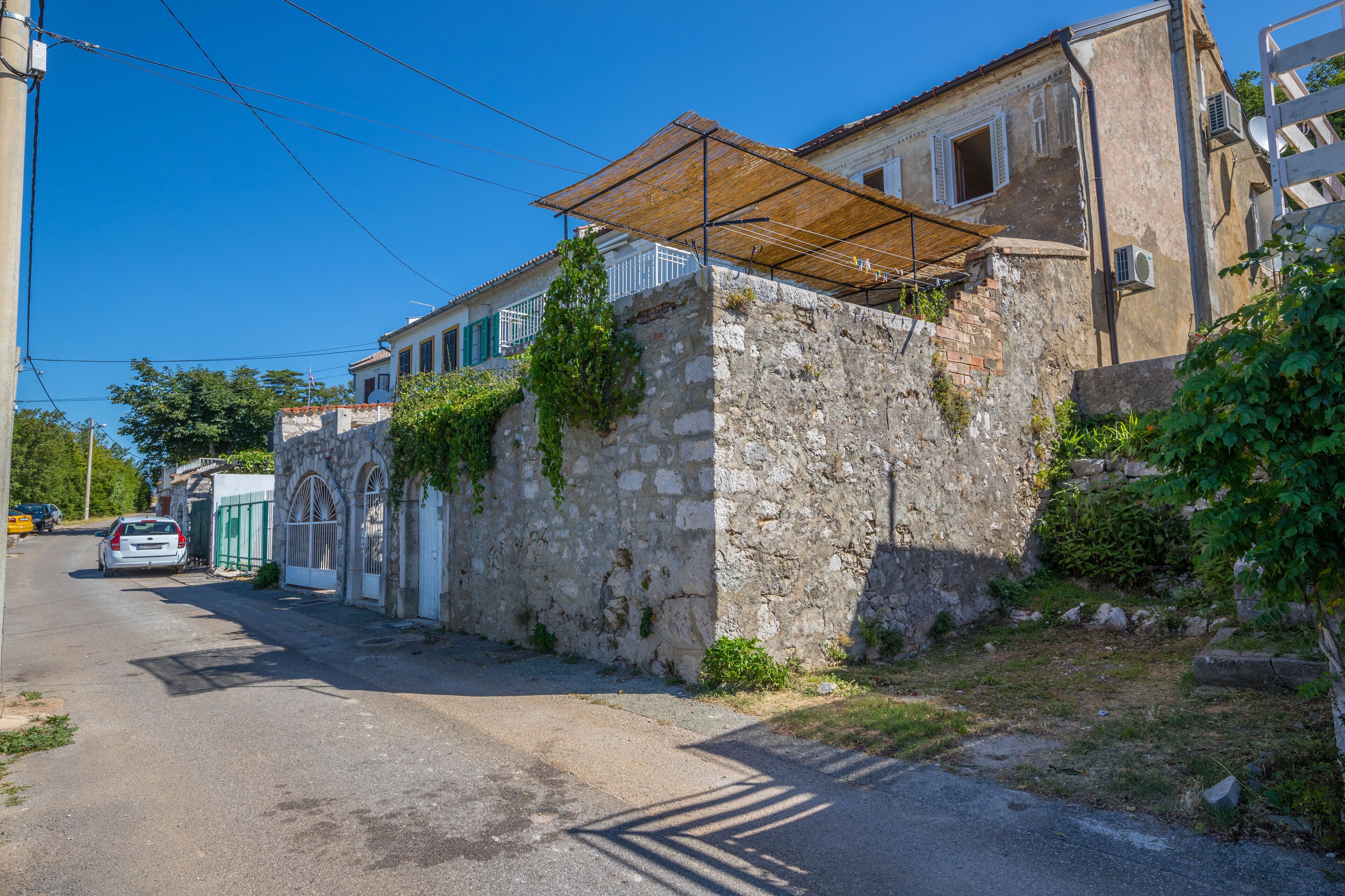 Una calle estrecha con un muro de piedra y un edificio con toldo de madera.
