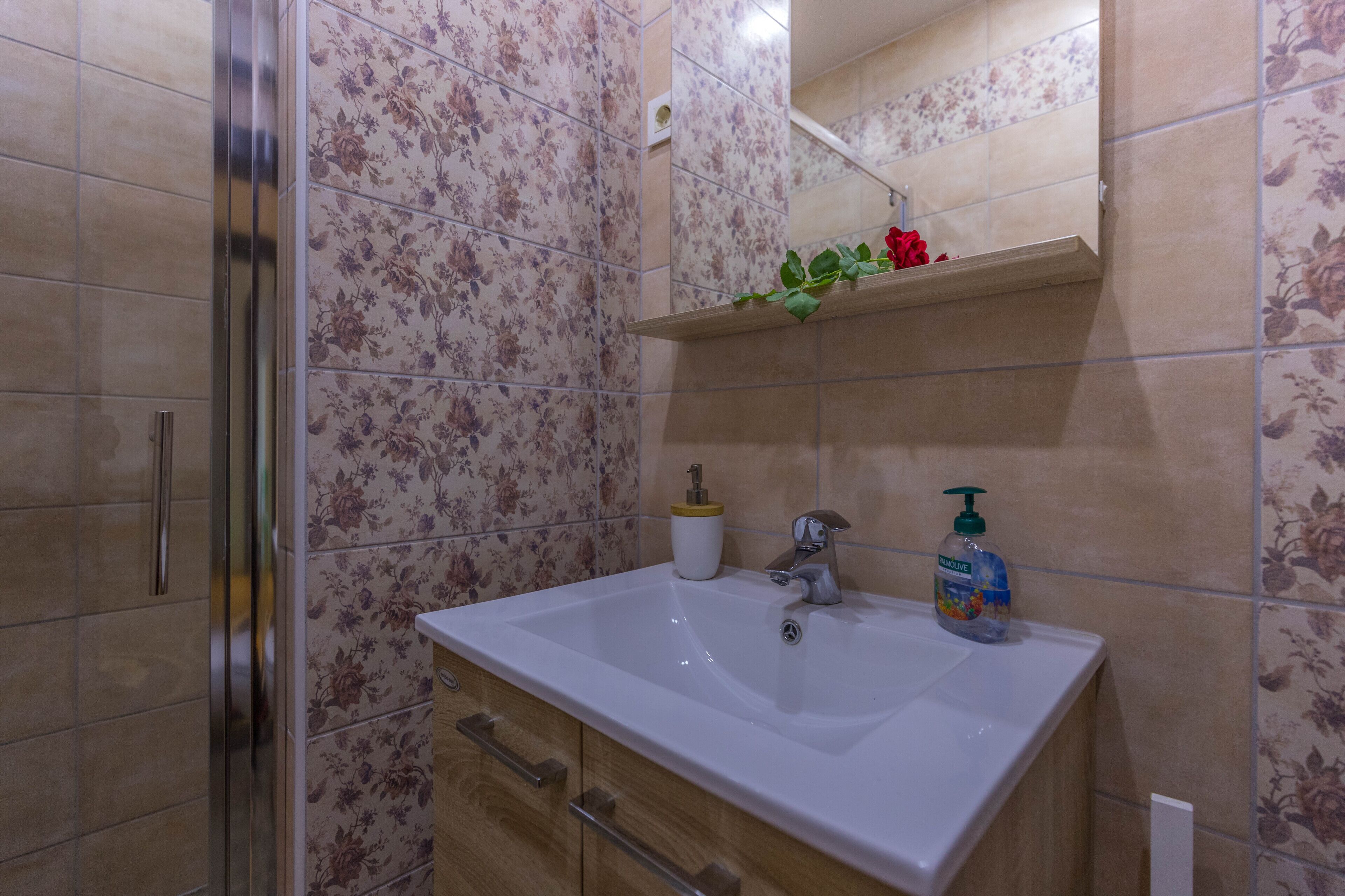 Un baño con lavamanos blanco, un espejo y ducha.