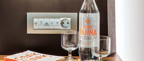 A book titled 'Cork Dork' by Bianca Bosker, a bottle of Acqua Panna water, and two glasses on a wooden table.