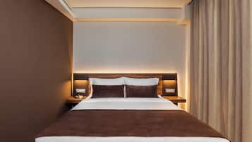 A hotel room with a large bed, a nightstand with a lamp, and a headboard with built-in lighting.