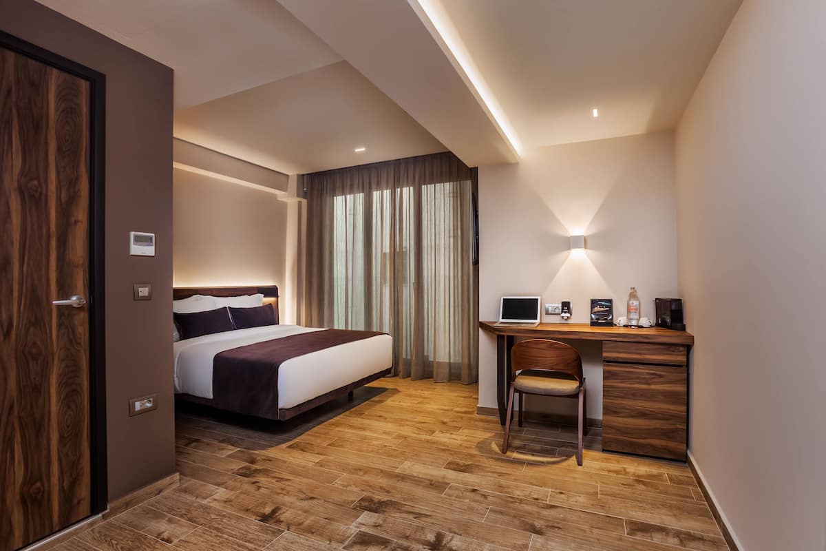 Une chambre d’hôtel avec un lit, un bureau, une chaise et des rideaux.