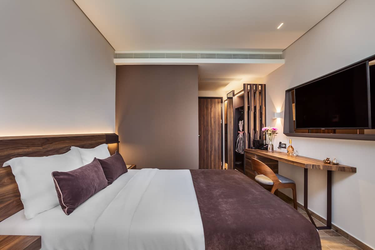 Une chambre d’hôtel moderne avec un grand lit, un bureau et une télévision.