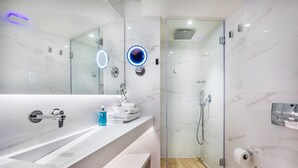 Un baño moderno con tocador de mármol, cabina de ducha de vidrio y retrete.