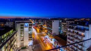 Un paisaje urbano al anochecer con edificios iluminados y una calle concurrida.