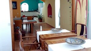 A dining area with wooden tables and chairs, a potted plant, and a surfboard on the wall. - TEGUISE OLD HELMET (Teguise)
