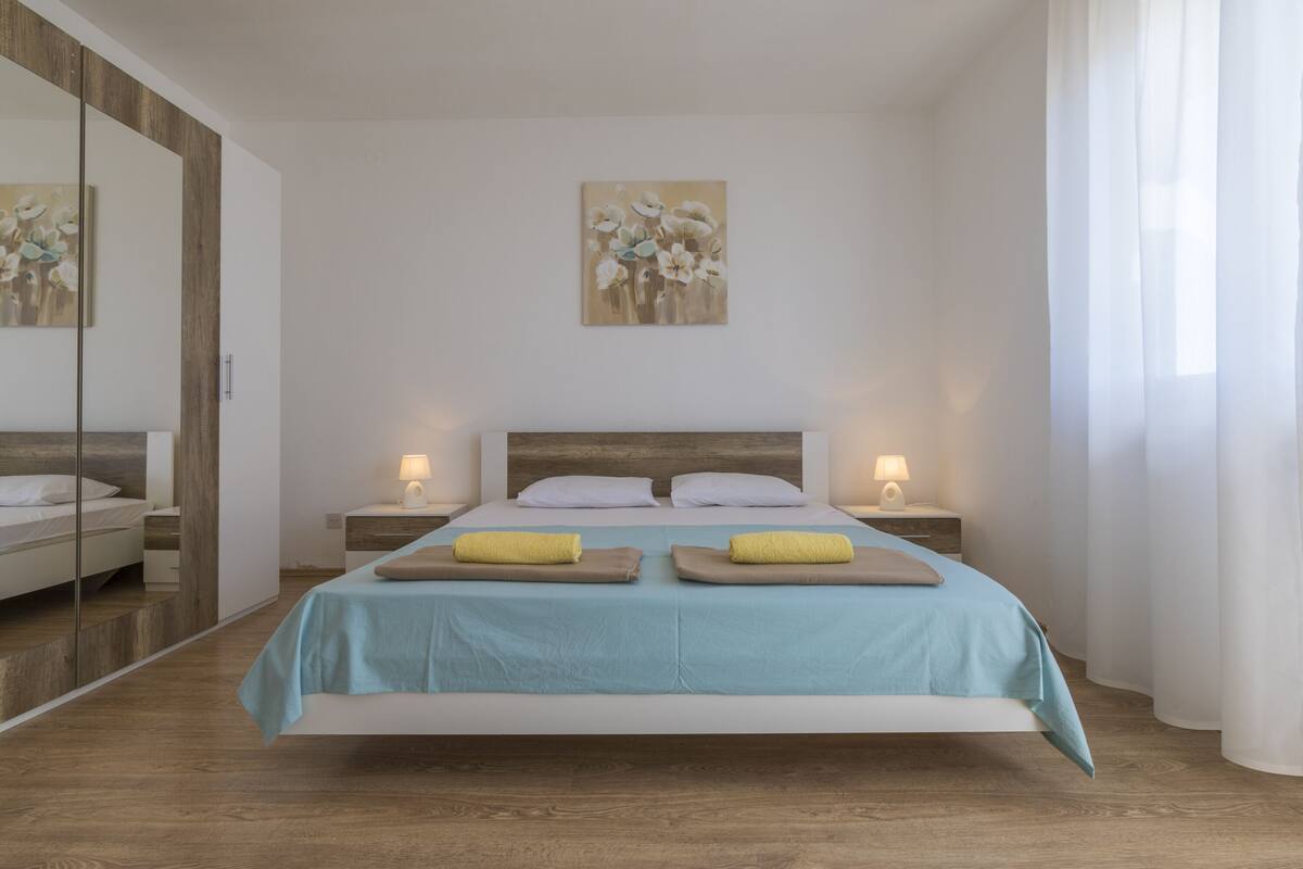 A modern bedroom with a bed, nightstands, and a painting on the wall.