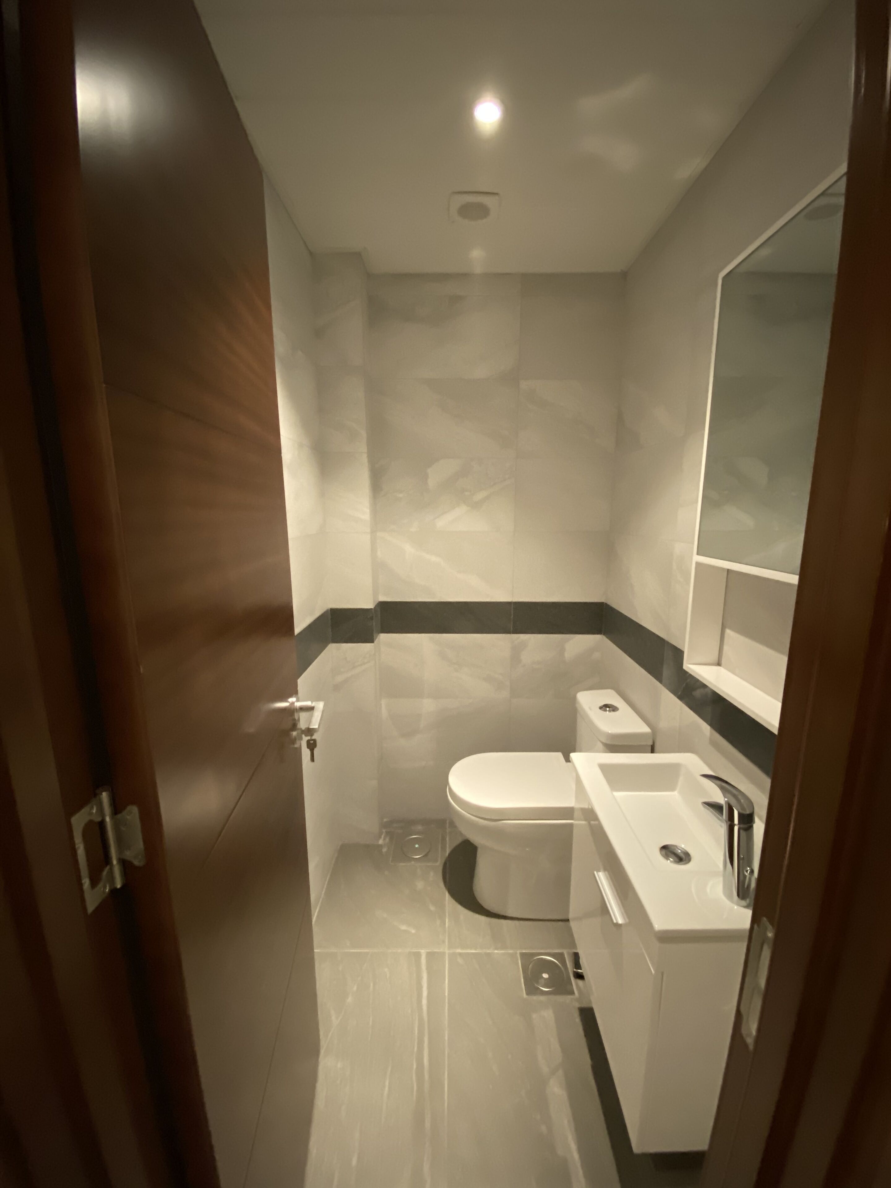 A modern bathroom with a toilet, sink, and mirror.
