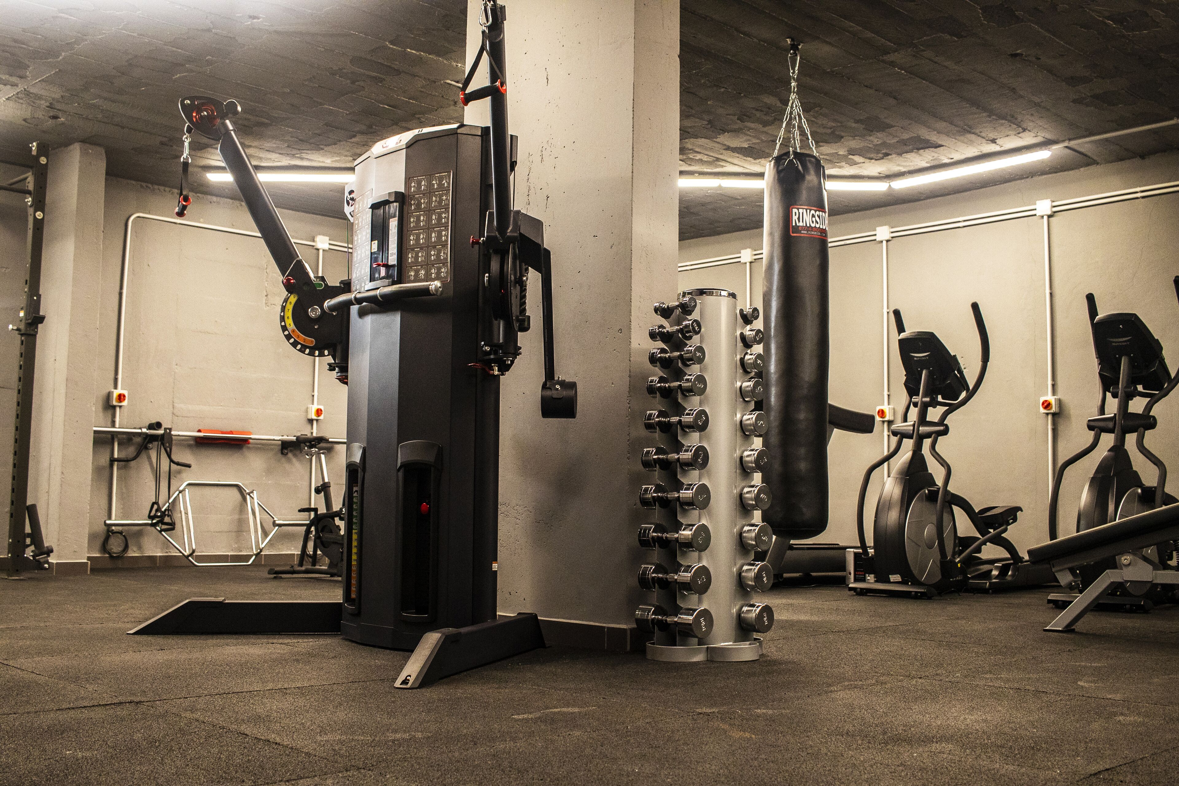 Et fitnesscenter med forskellig træningsudstyr, heriblandt boksebold, styrkemaskiner og konditionsmaskiner.