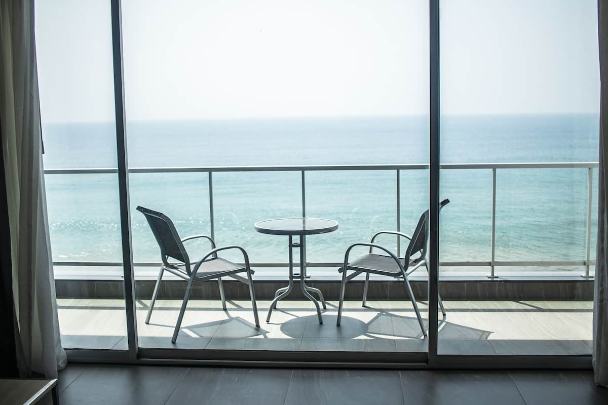 A balcony with two chairs and a table, overlooking the ocean.
