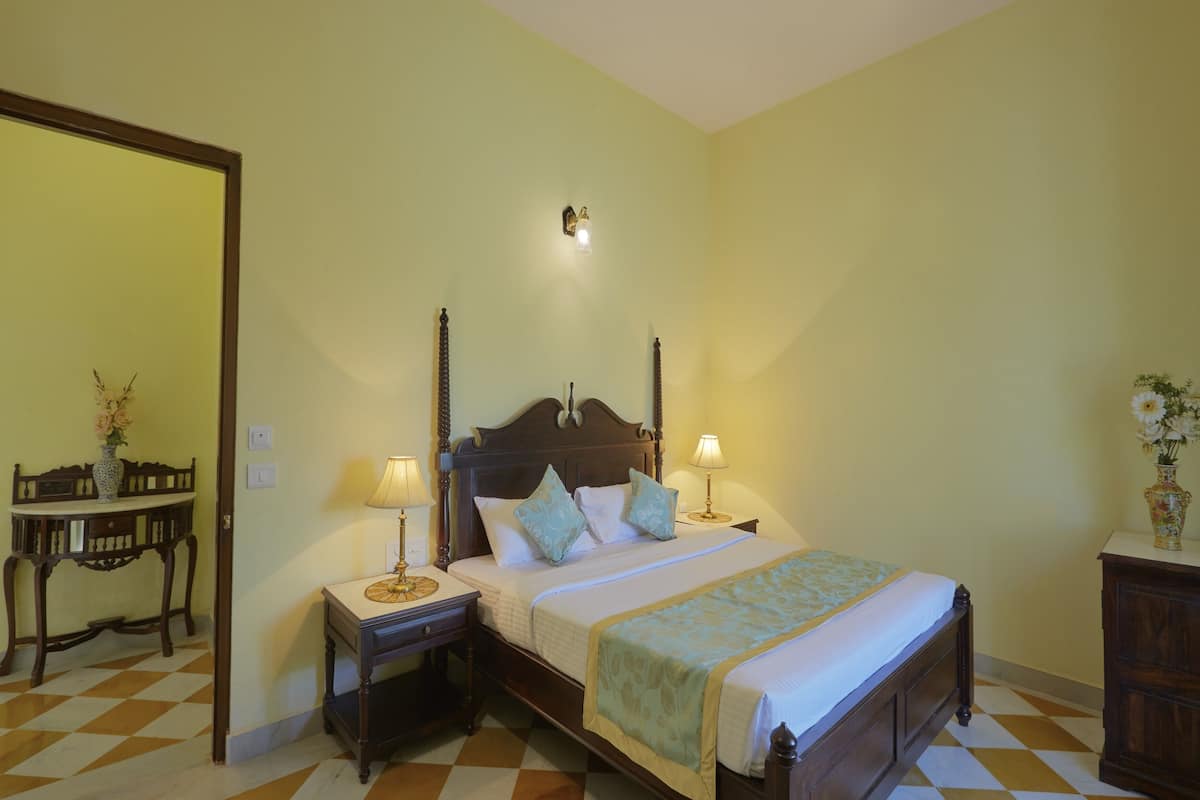 Une chambre à coucher avec un lit en bois, deux tables de chevet avec des lampes, une table de nuit, une commode et un miroir au mur.