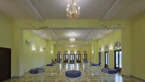 A spacious hall with a checkered floor, white chairs, and tables arranged for dining.