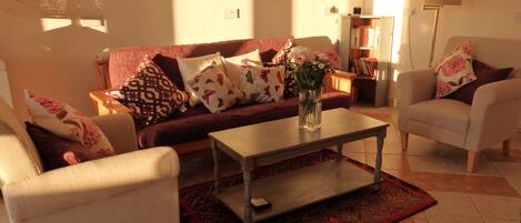 Een woonkamer met een bank, twee fauteuils, een bijzettafeltje en een kamerkleed met patroon.