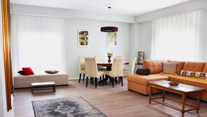 Una sala de estar moderna con un sofá, una mesa de comedor con sillas, una mesa de centro y una alfombra.
