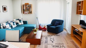 Una sala de estar moderna con un sofá azul, un sillón azul, una mesa de centro de madera y una estantería.