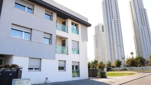 Un moderno edificio de apartamentos con varios balcones, ventanas amplias y un acceso con portón.