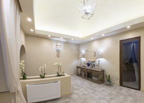 Un baño moderno con una decoración color beige, un espejo grande, un tocador con un radiador blanco y una lámpara en el techo.
