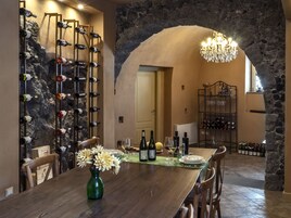 Un comedor con un arco de piedra, estanterías para vino y una araña.