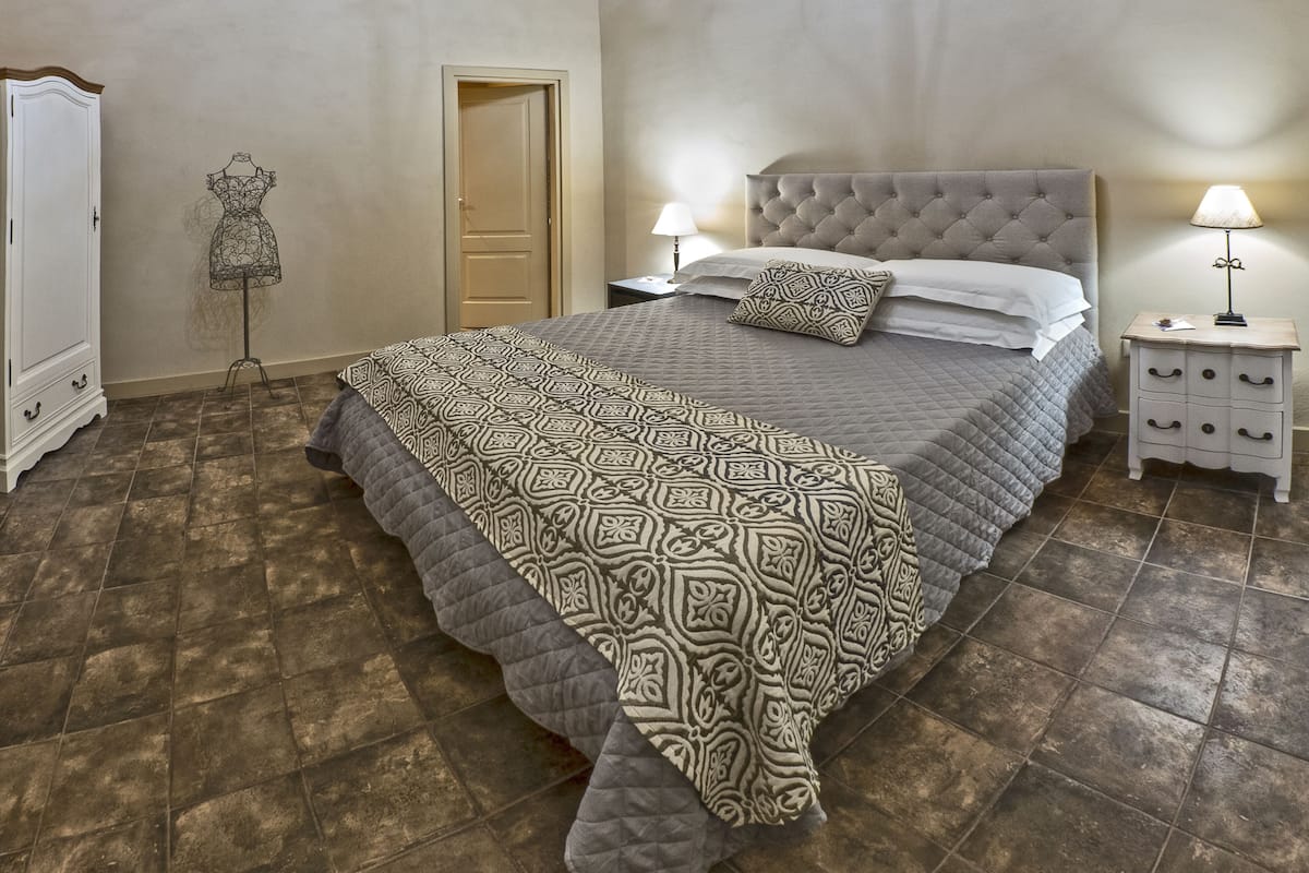A bedroom with a large bed, a nightstand, a dresser, and a door.