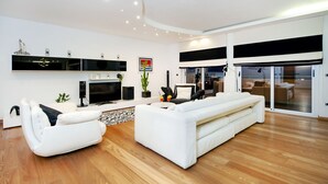 A modern living room with a white sofa, a flat-screen TV, and a large window.
