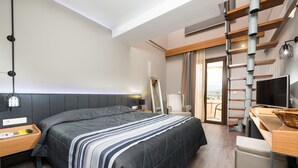 A modern hotel room with a large bed, a desk with a computer, a chair, a TV, and a balcony with a view. - Atrium Hotel Thassos by GHH (Thasos)