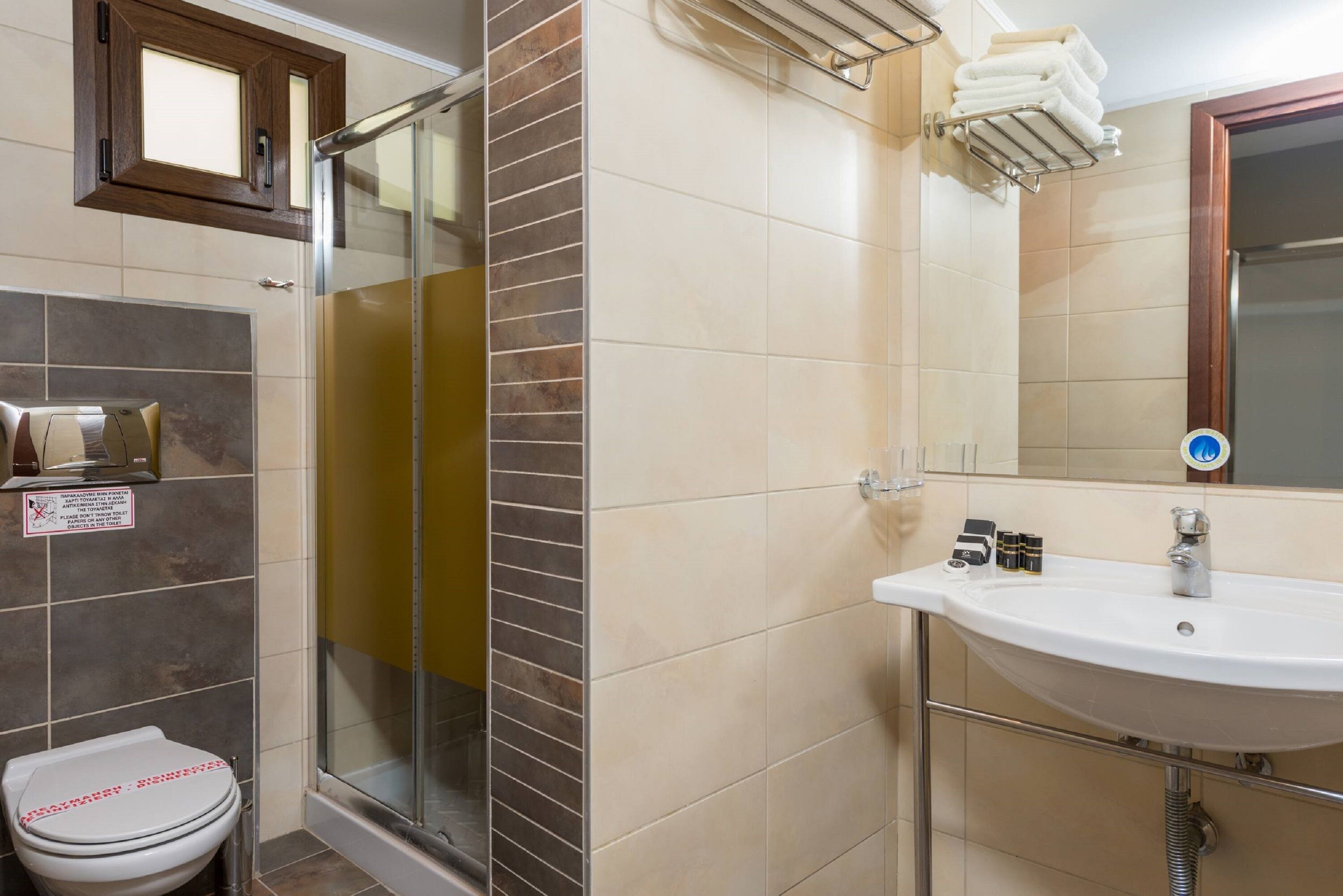 A bathroom with a shower, toilet, sink, and a mirror.