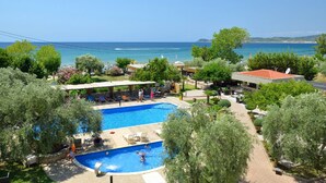 A swimming pool with a view of the sea, surrounded by trees and outdoor seating. - Atrium Hotel Thassos by GHH (Thasos)