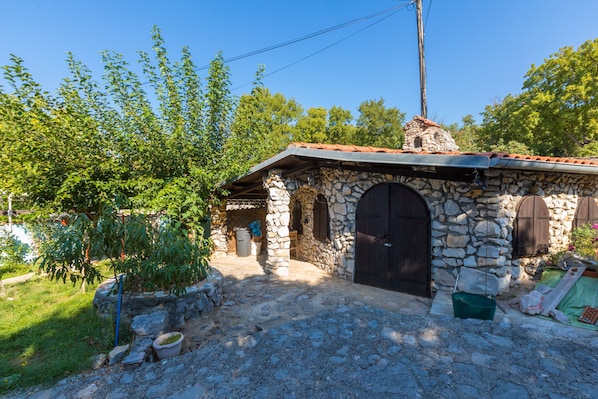 Ein Haus aus Stein mit einem Ziegeldach, einem Steinkamin und einem kleinen Garten.