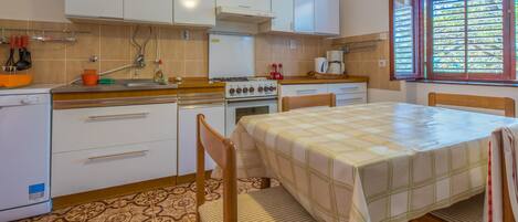 Una cocina compacta con armarios blancos, estufa y comedor con mesa y sillas.