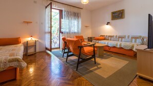 Una sala de estar acogedora con un sofá, sillas, una mesa y un televisor.