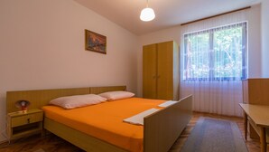 Un dormitorio con una cama de madera, una mesita de noche, un escritorio y un armario.