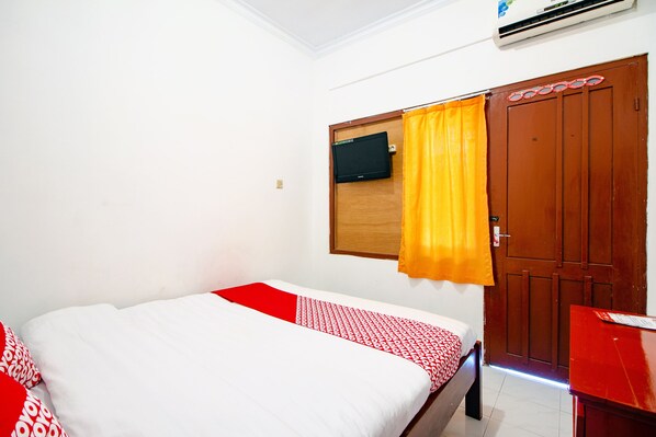 A hotel room with a bed, a wooden wardrobe, and a small desk. - Super OYO 1788 House 24 (Yogyakarta)