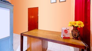 A reception desk with a vase of yellow flowers, a red curtain, and two framed certificates on the wall.