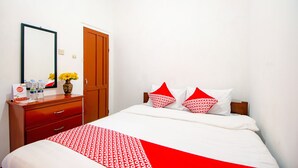 A hotel room with a bed, a wooden dresser, a mirror, and a door.